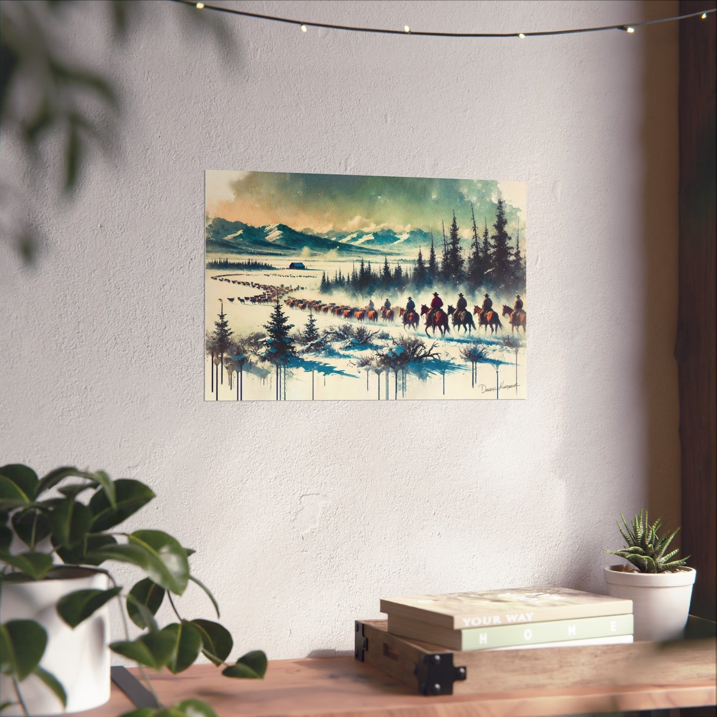 Framed artwork of a snowy landscape with cowboys on horseback hanging on a wall above a desk.