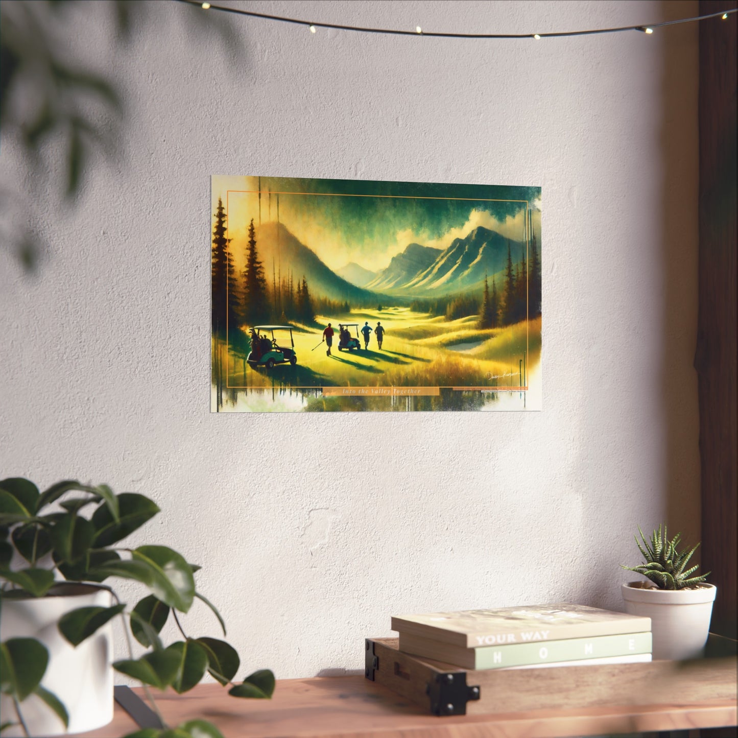 Scenic painting of a mountain landscape with golfers on a course, hanging on a wall above a desk.