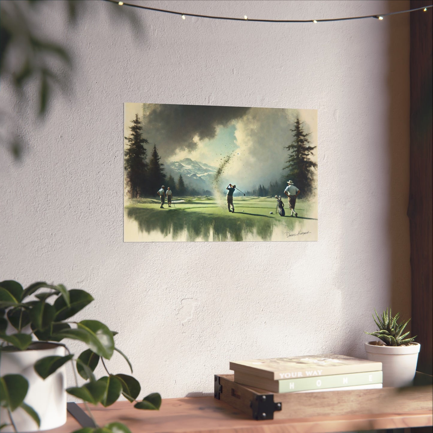 Poster of golfers on a green with mountains in the background, hanging on a wall above a desk.