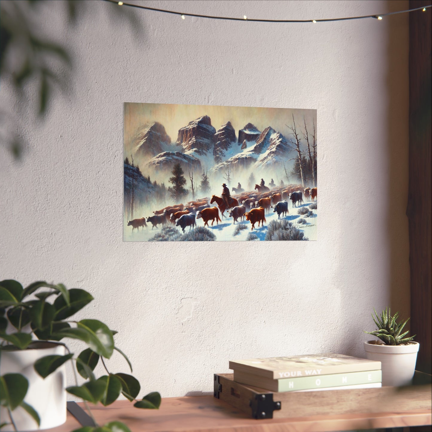 Framed painting of a snowy landscape with cowboys and animals on a wall above a desk.