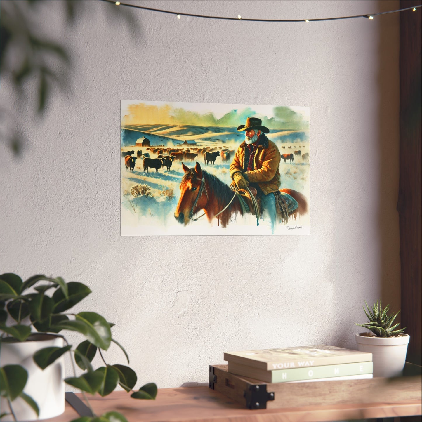 Poster of a cowboy on a horse with cattle in a field, hanging on a wall above a desk.