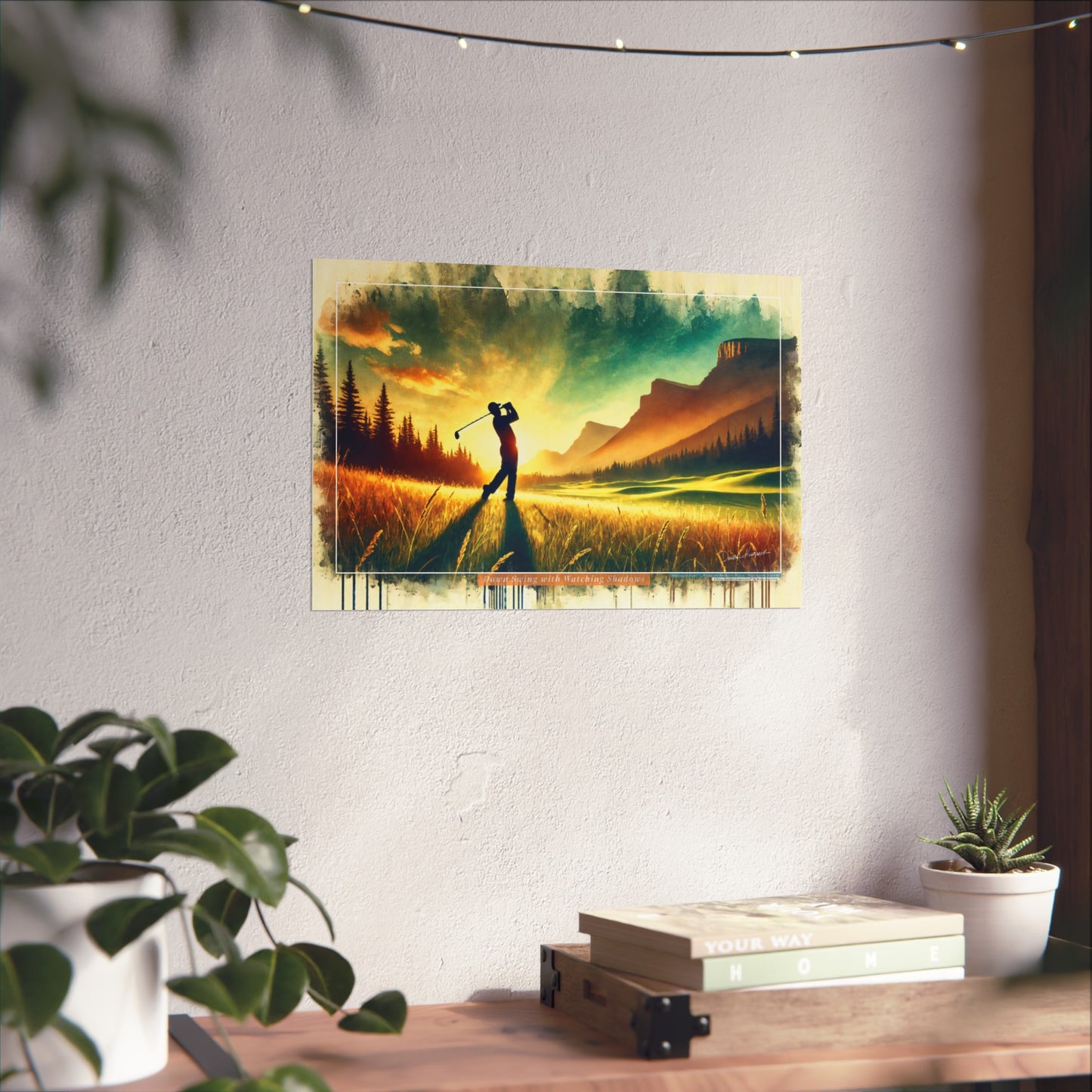 Wall art of a golfer in a scenic landscape on a white wall with plants and books below.