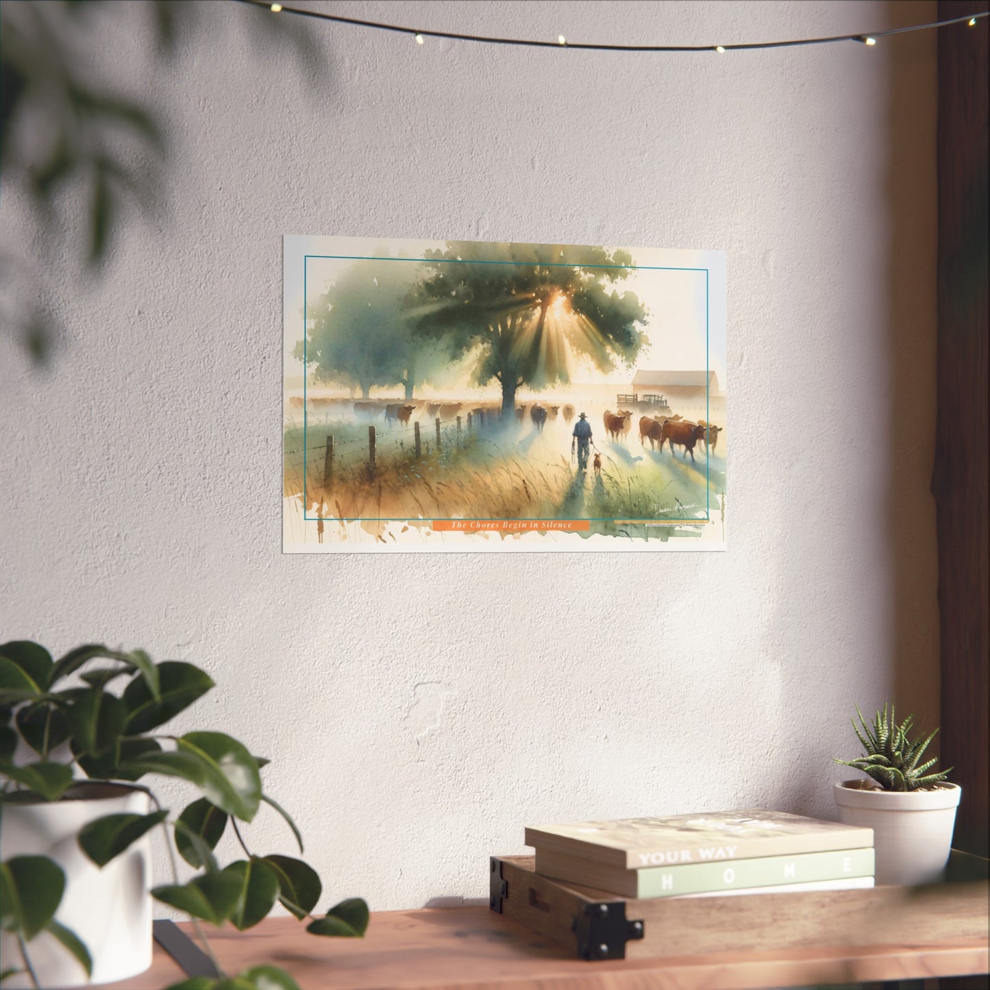 Poster of a scenic landscape with a farmer and cows on a wall above a desk with plants.