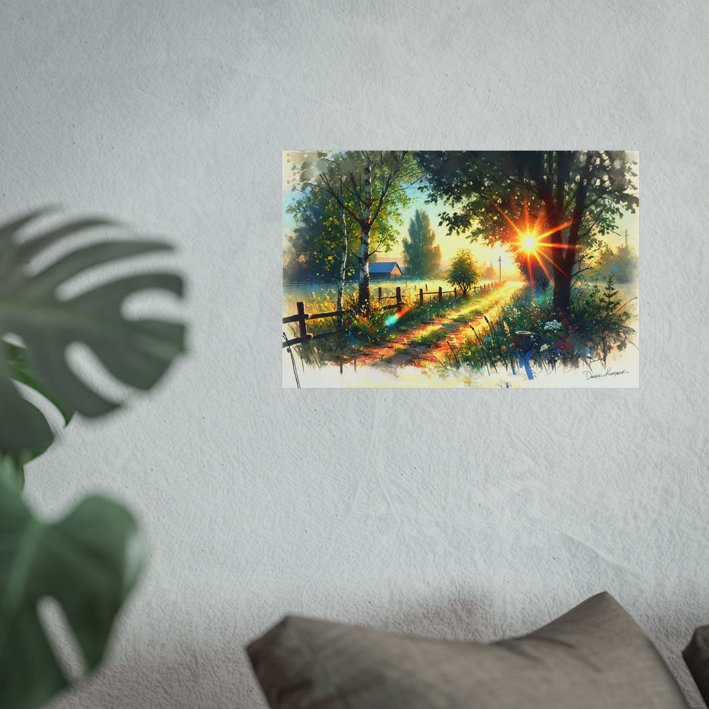 Poster of a sunset over a forest scene on a wall with a plant and pillow in the foreground.