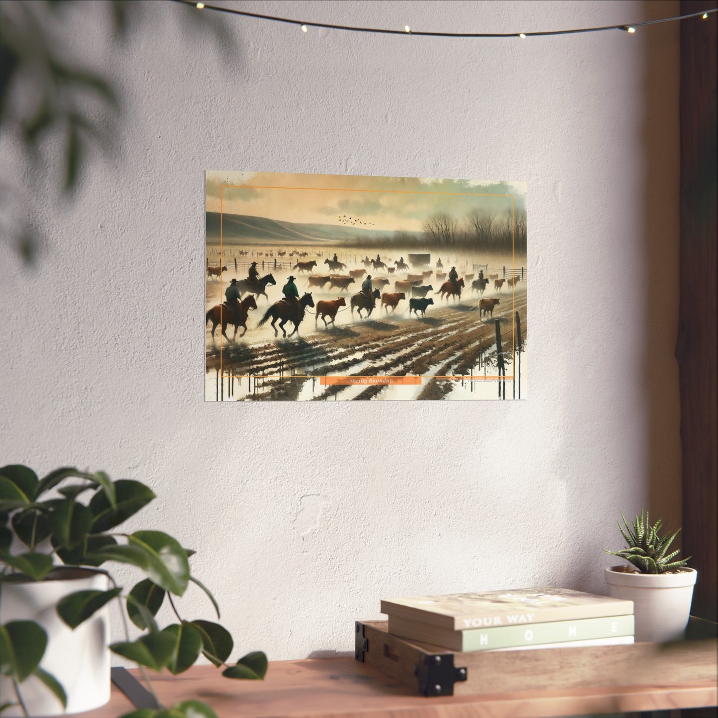 Artistic depiction of a historical scene with cowboys on horseback, framed on a wall above a desk.