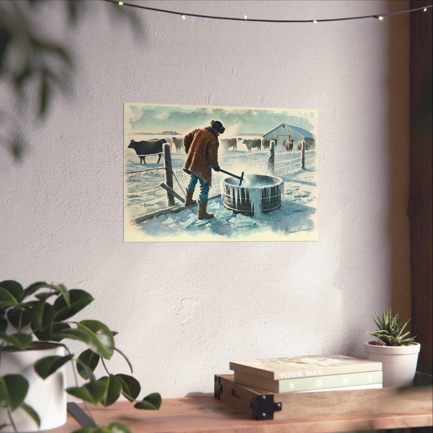 Poster of a Cowboy with a cow in a snowy landscape on a wall above a desk with plants.