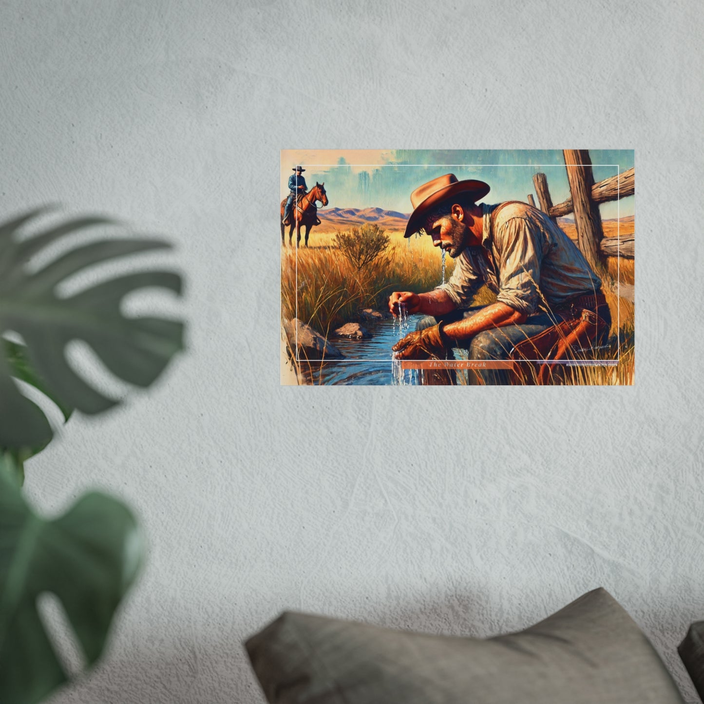 Poster of a cowboy by a water hole with another cowboy on horseback in the background, on a light gray wall.