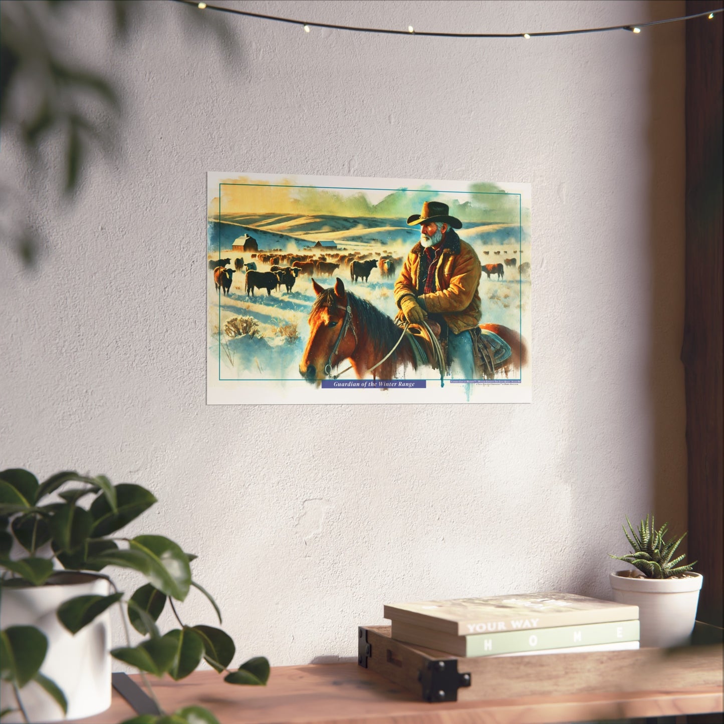 Poster of a cowboy on horseback with cattle hanging on a wall above a desk with plants.
