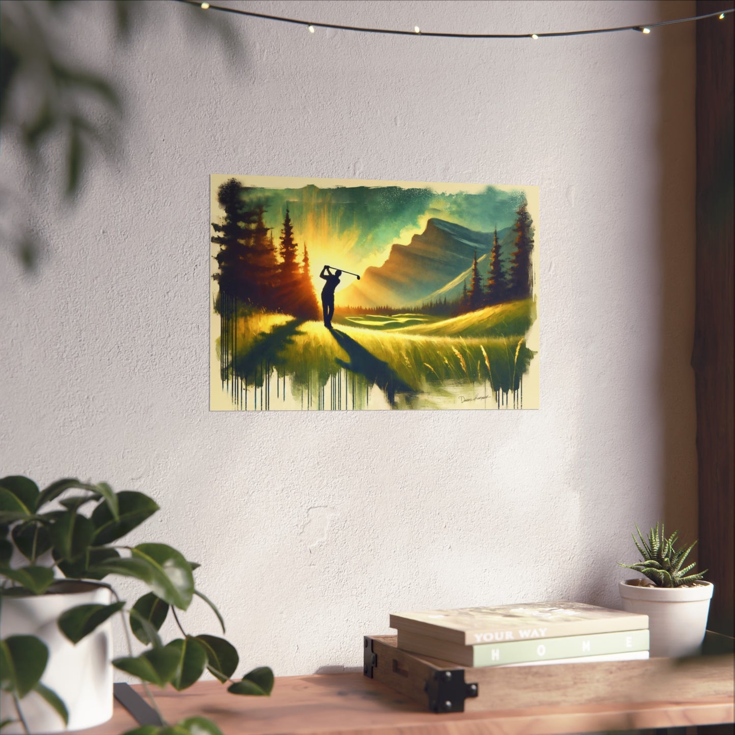 Giclee print of a golf player on a mountain landscape hanging on a wall above a desk with plants.