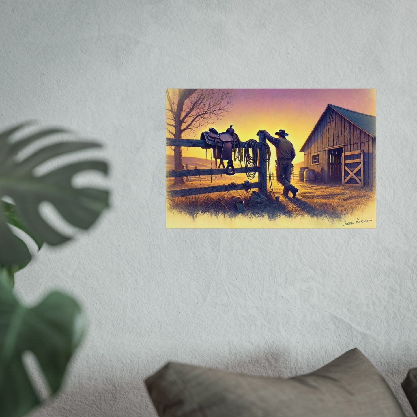 Framed artwork of a cowboy with a horse on a fence at sunset, displayed on a wall.