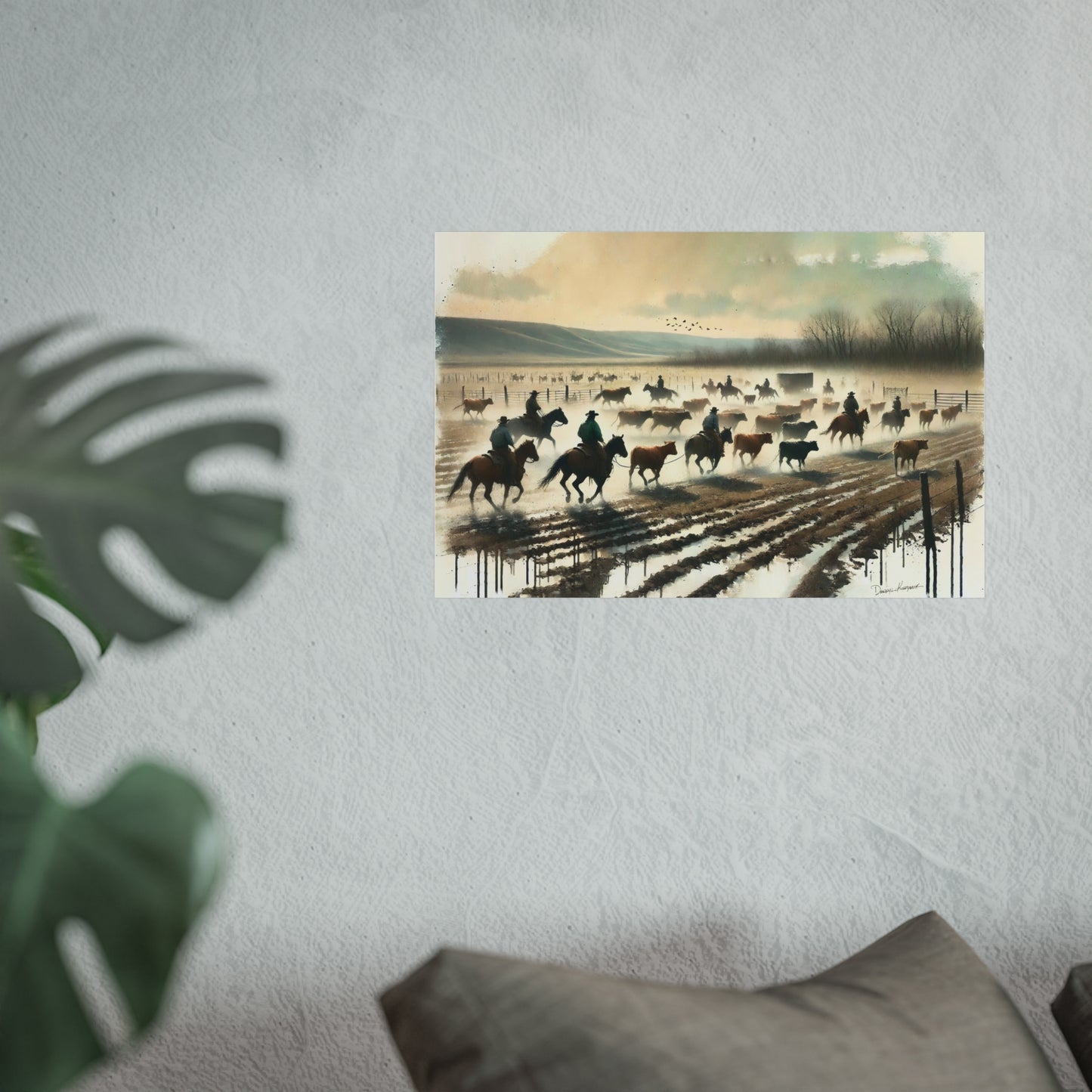 Art print of a cowboy scene on a wall with a plant and pillow in the foreground.