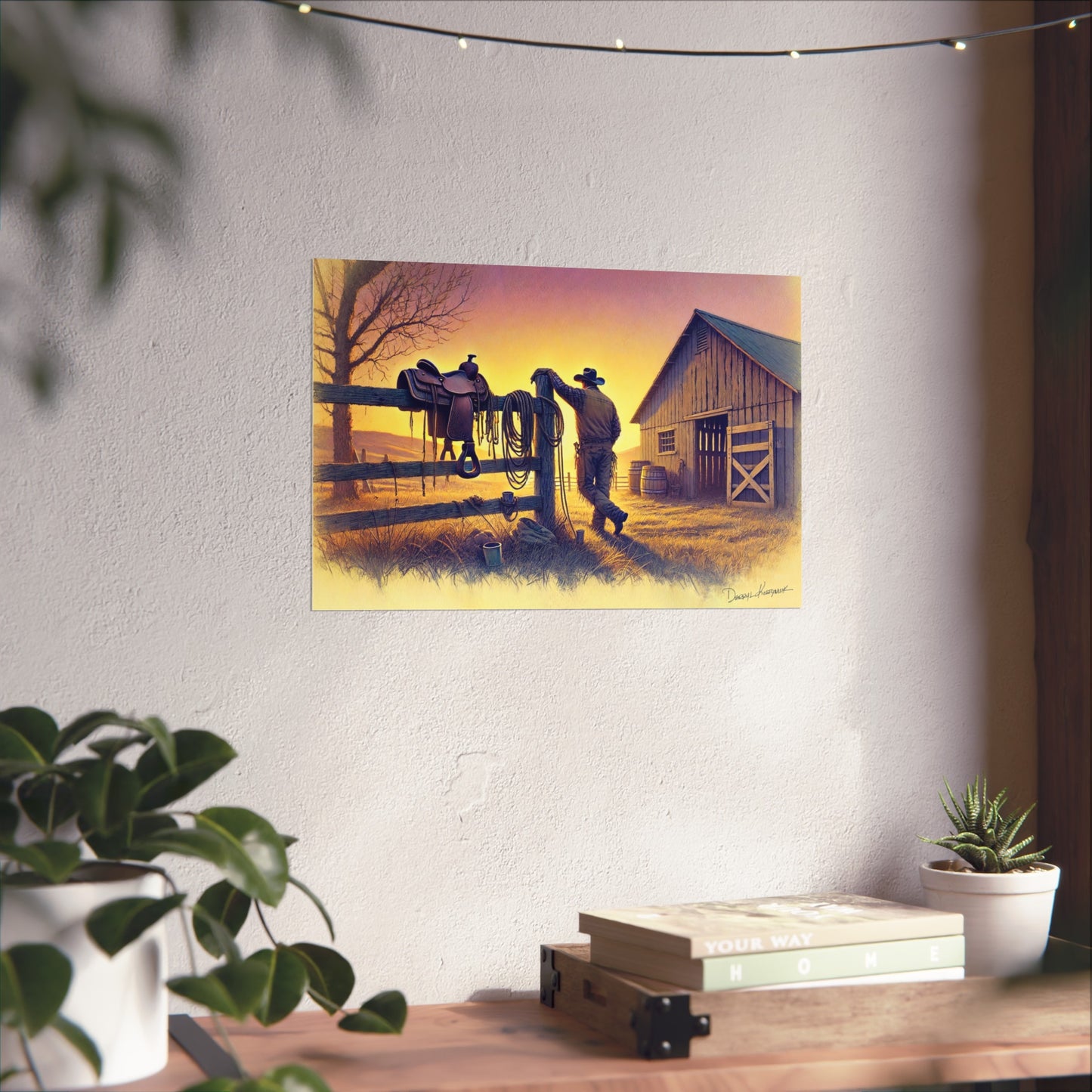 Painting of a cowboy with a horse on a fence in front of a barn, hanging on a wall above a desk.