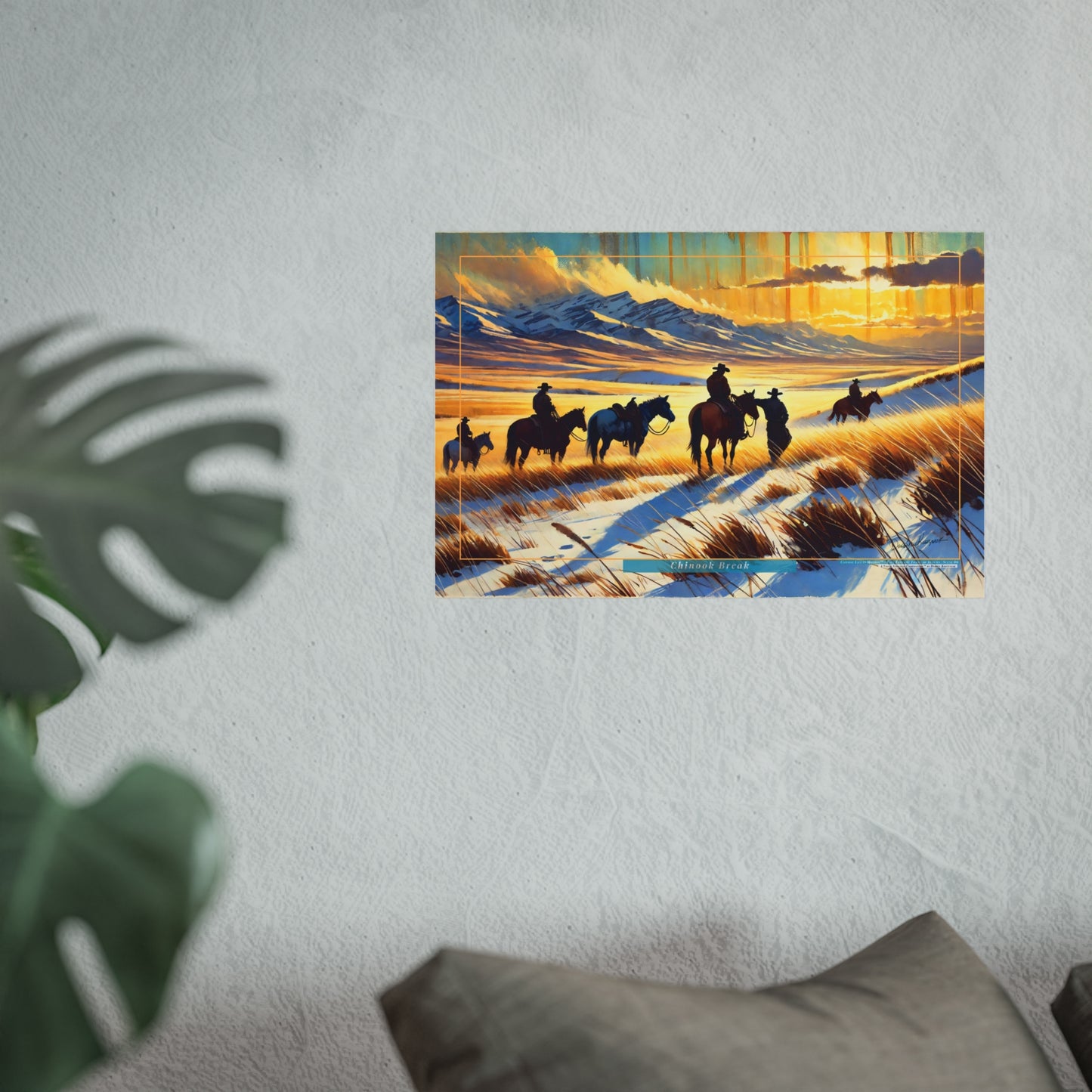 Framed artwork of cowboys on horses against a mountainous landscape with a sunset.