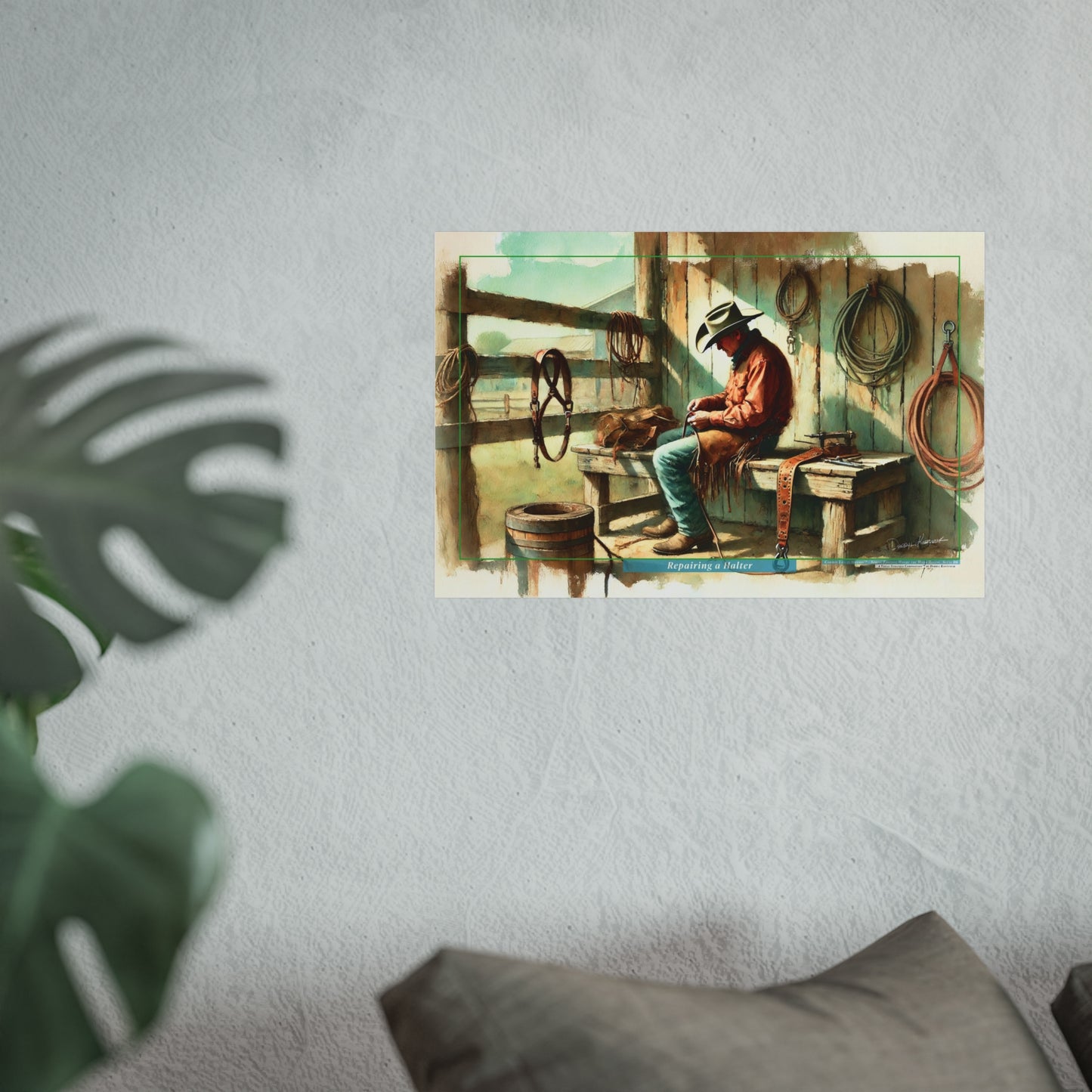 Art print of a cowboy sitting in a corral on a wall with a plant and pillow in the foreground.