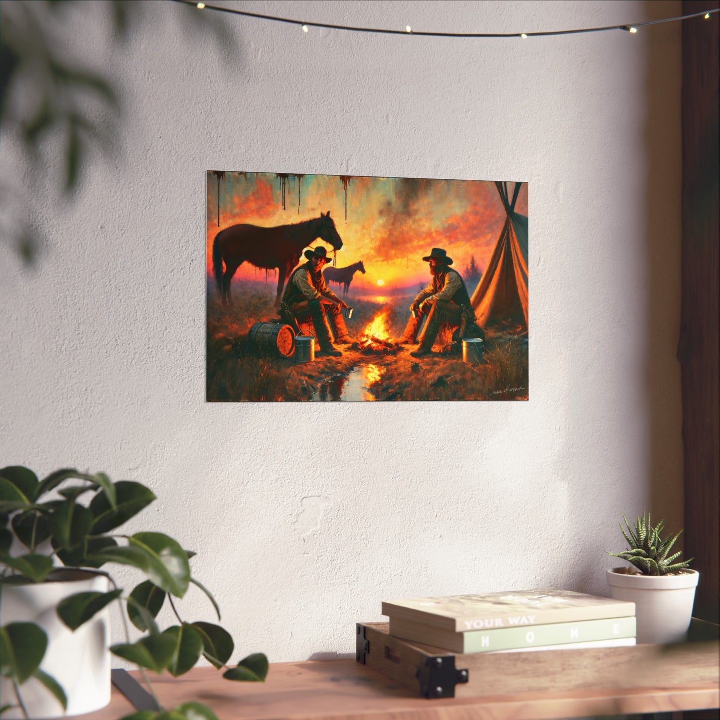 Canvas print of two cowboys by a campfire with horses on a white wall, below string lights.