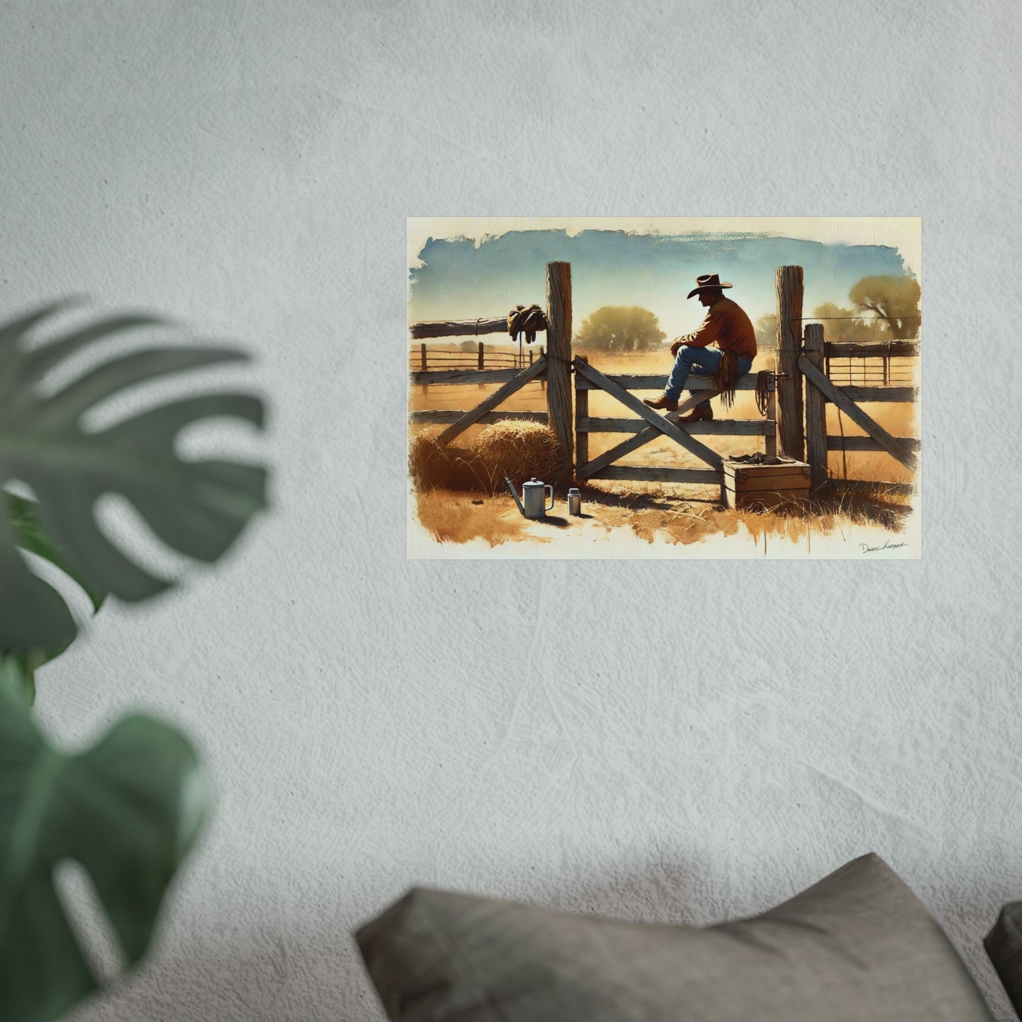 Poster of a cowboy sitting on a fence with a scenic background, placed on a wall.