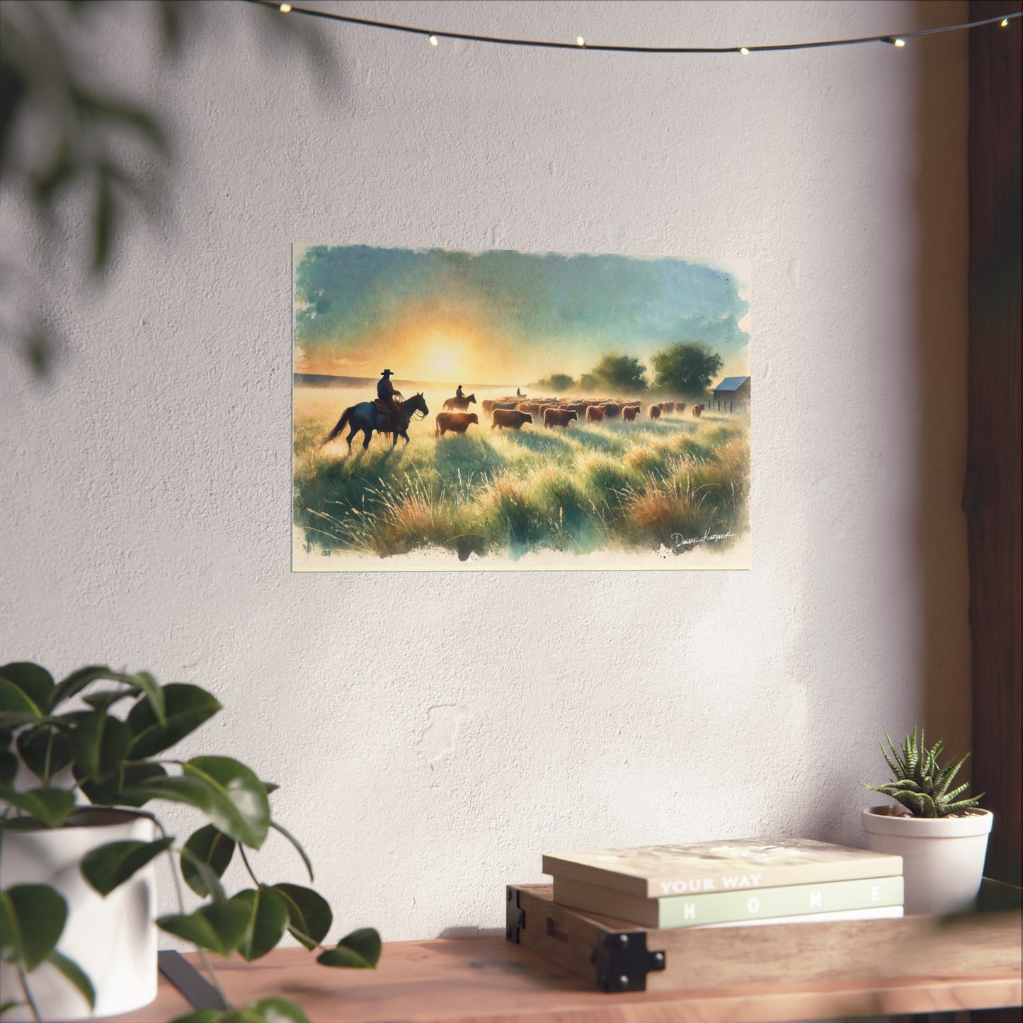 Painting of a sunset scene with cowboys on horses hanging on a wall above a desk.