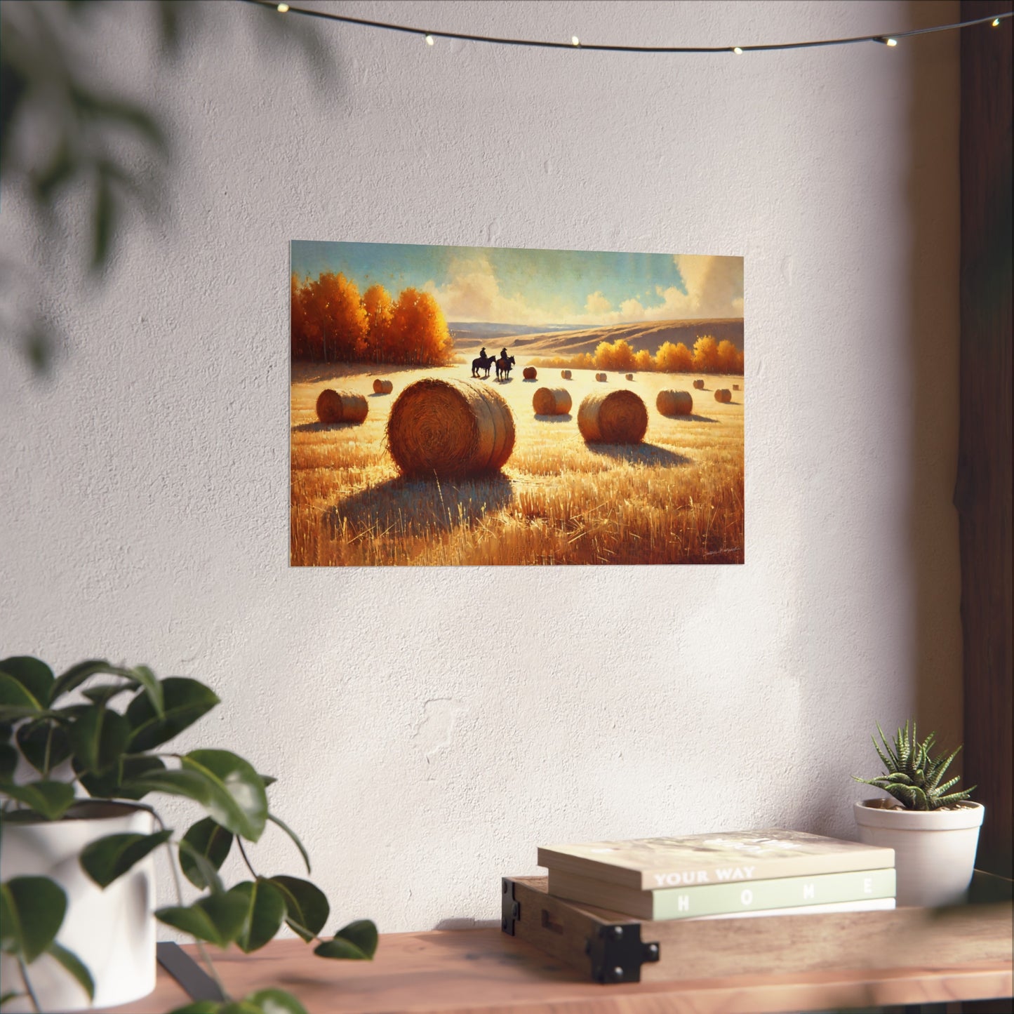 Painting of a rural scene with cowboys, hay bales and trees on a wall above a desk.