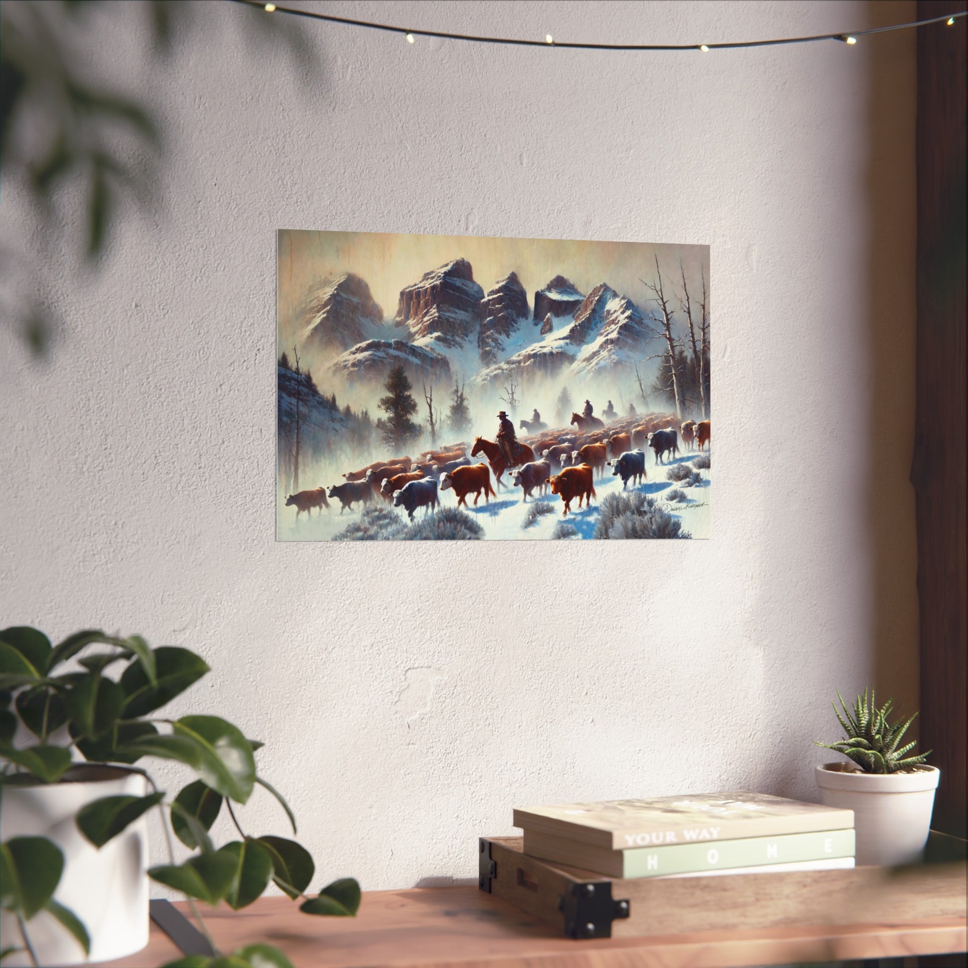 Framed painting of a snowy landscape with cowboys and animals on a wall above a desk.