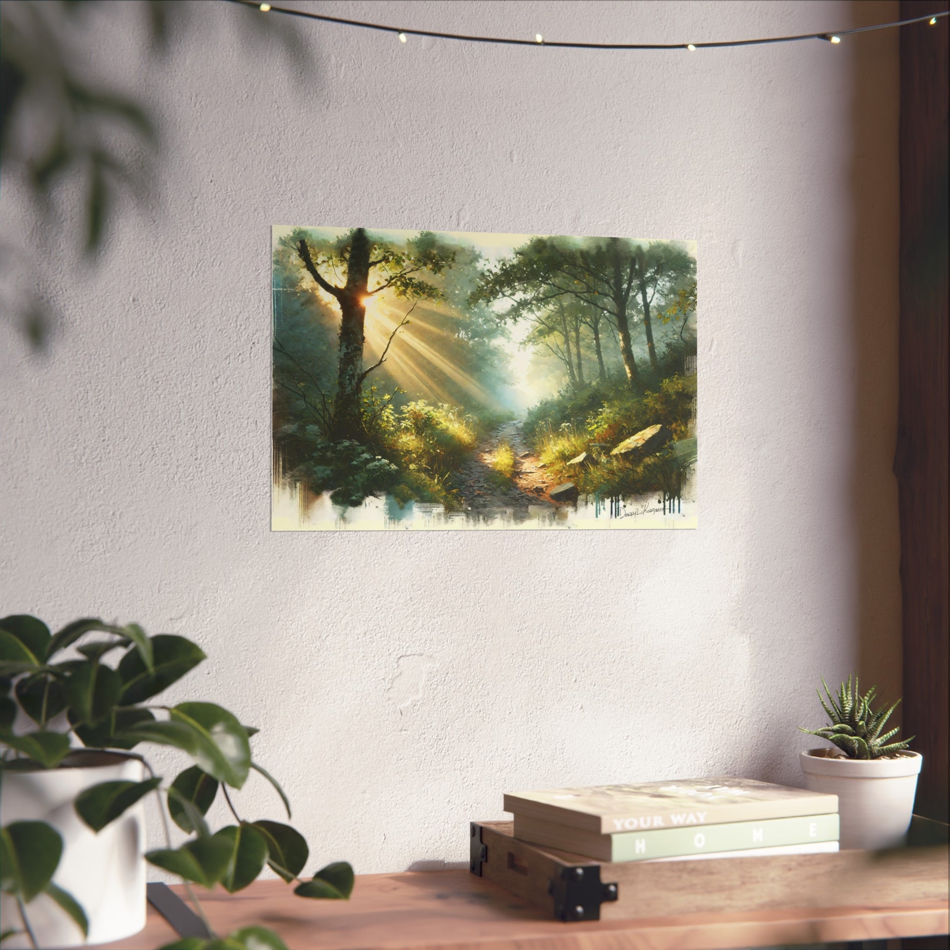 Framed artwork of a forest scene with sunlight on a wall above a desk with plants.