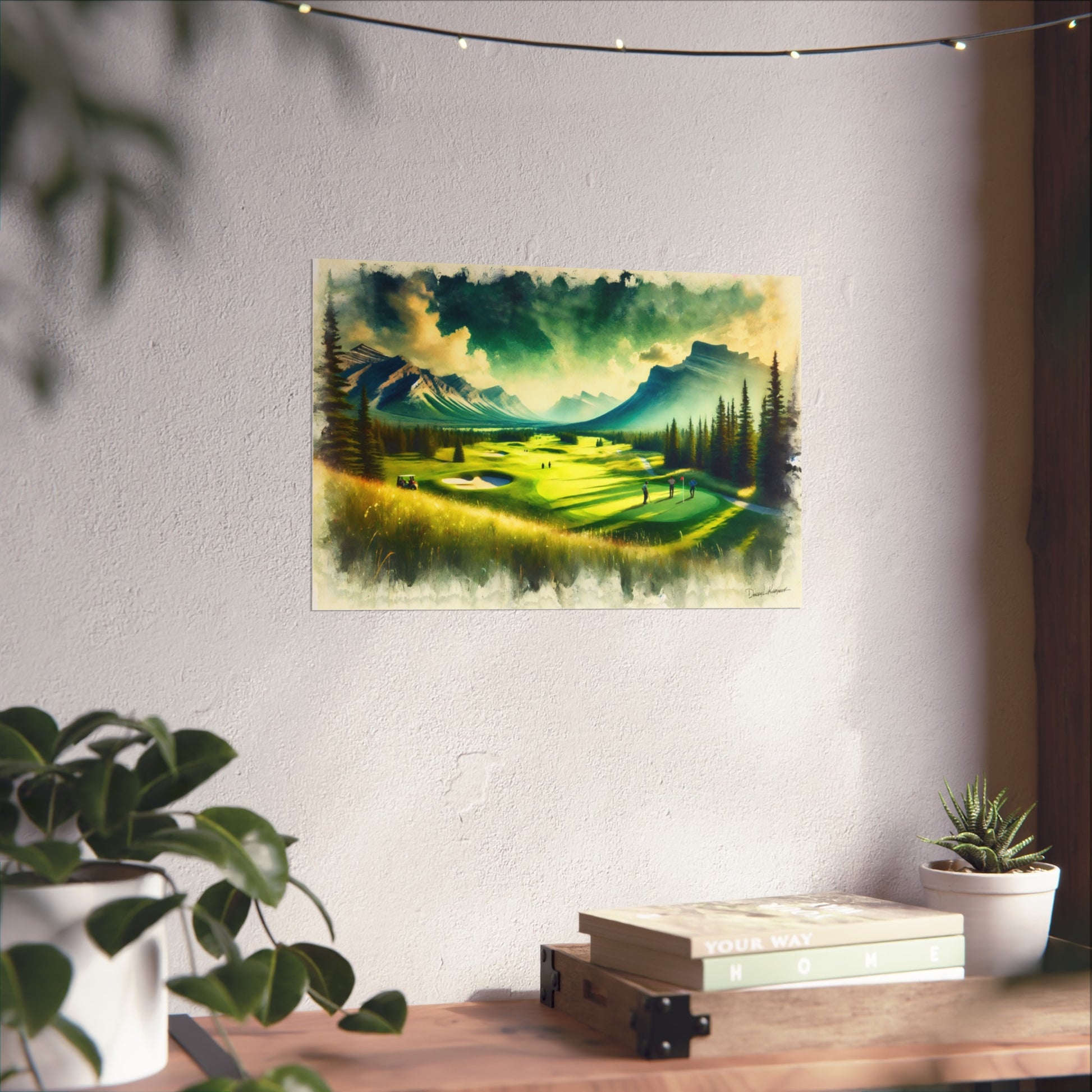 Scenic painting of a golf course with mountains on a wall above a desk with plants and books.